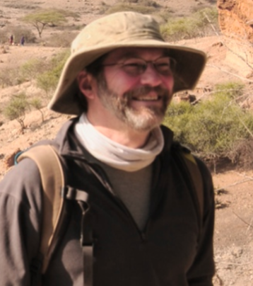 A headshot of Ted Gragson who is wearing a khaki hat and a brown shirt.