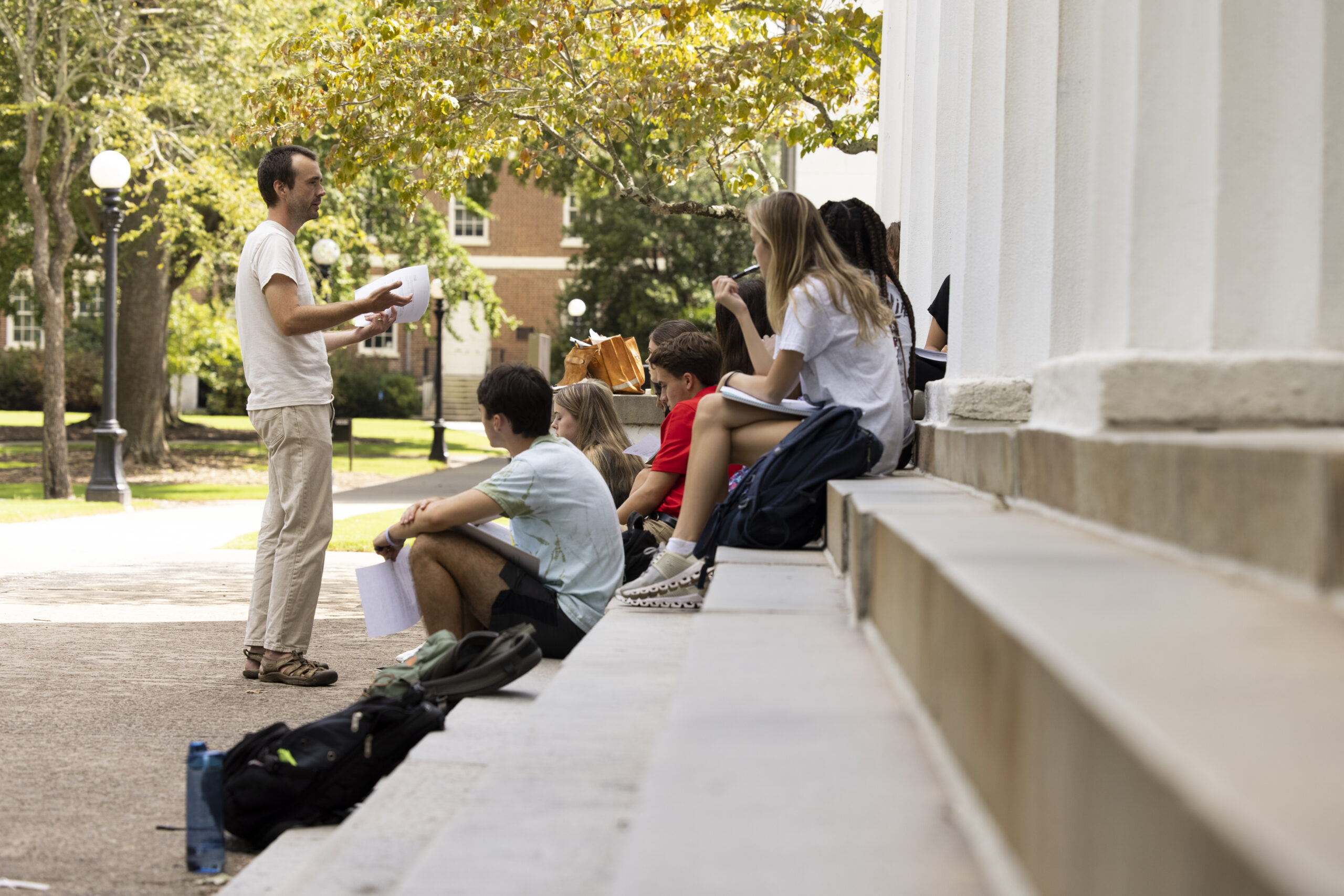 Instructor Stephen Brooks teaches his first year english composition class on the steps of the chapel.