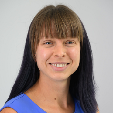 A photo of Alison Banka, who has shoulder-length brown hair and is wearing a sleeveless, periwinkle shirt.