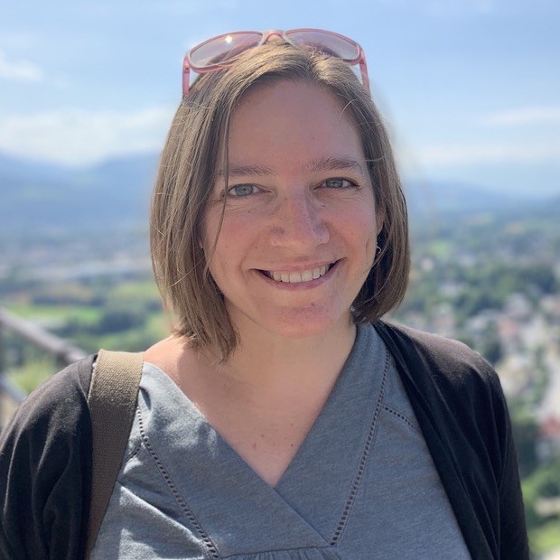 A photo of Amanda Rugenski, who has short brown hair and is wearing a blue shirt with a black cardigan.