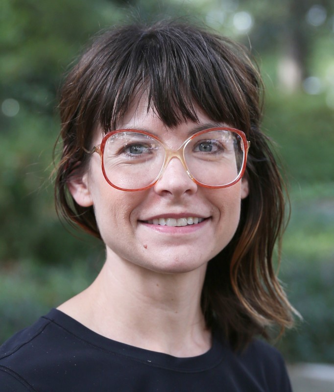 A photo of Melissa Kozak, who has long brown hair, red glasses, and is wearing a black shirt.